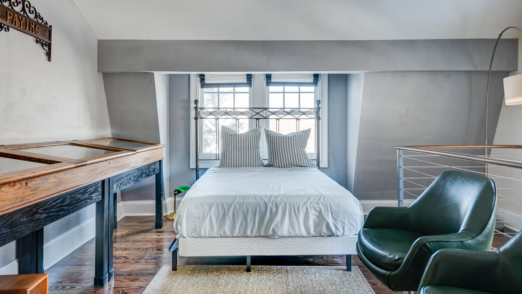 Un dormitorio con una cama bajo una ventana y un sillón verde cerca.