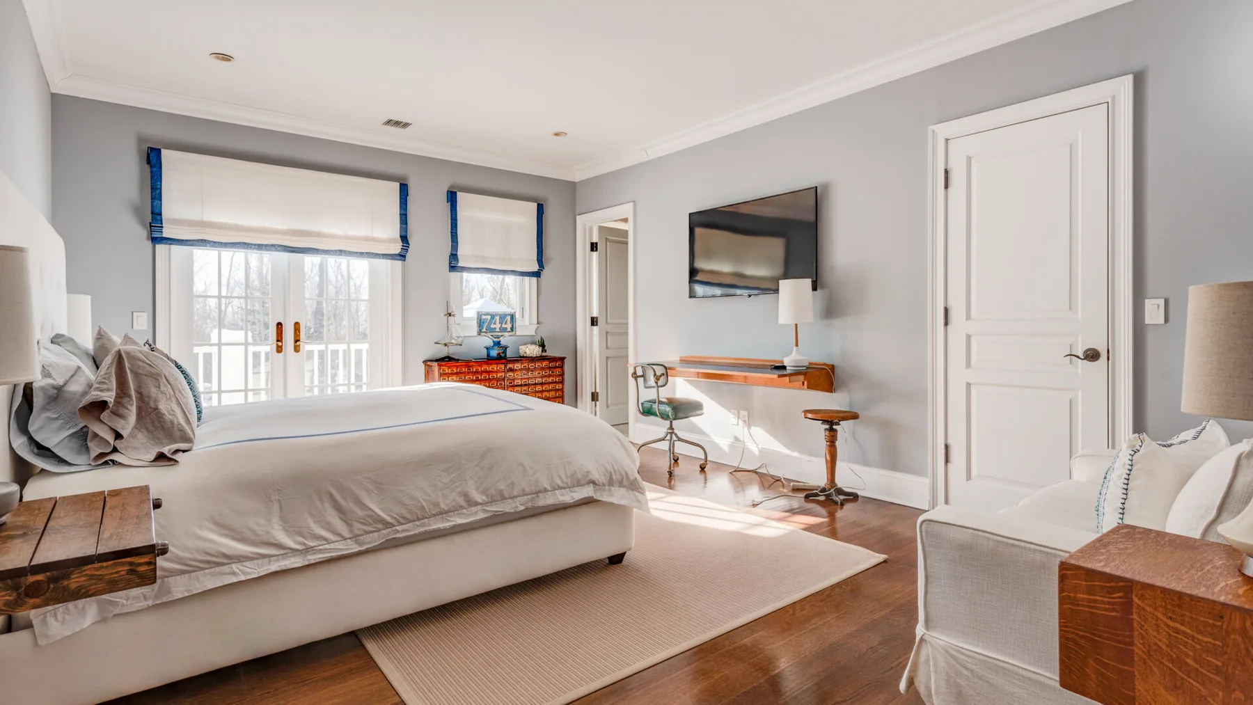 Un dormitorio con una cama grande, ventanas y un televisor en la pared.