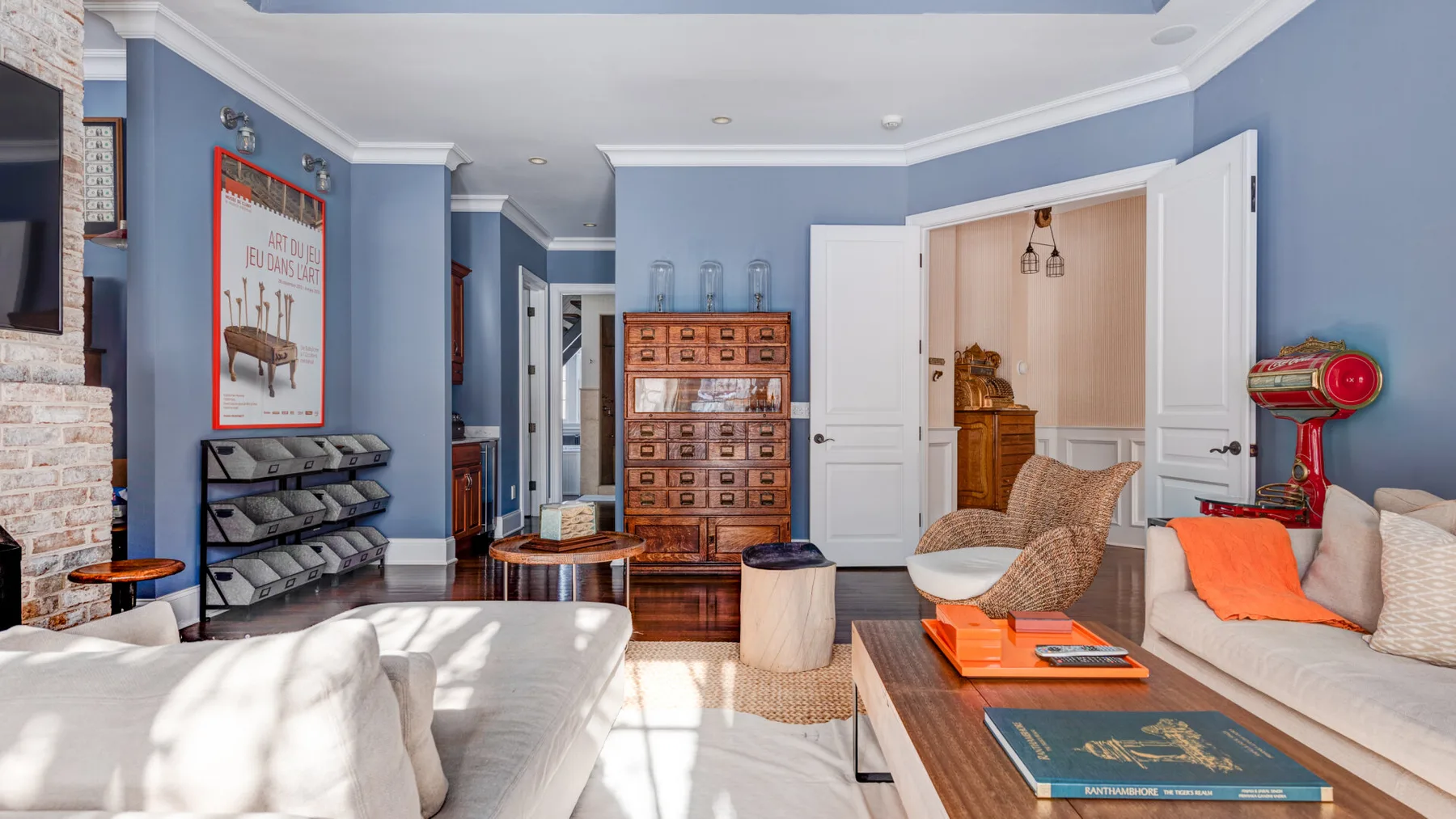 Una sala luminosa con paredes azules, sofás y un mueble de madera en el centro.