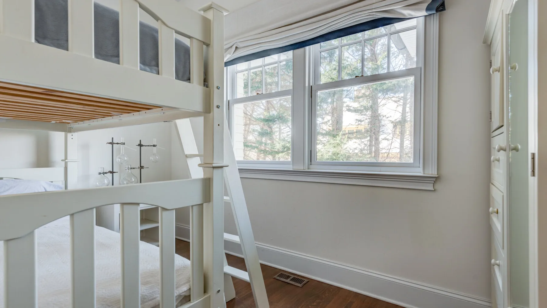 Un dormitorio luminoso con una cama elevada junto a grandes ventanas.