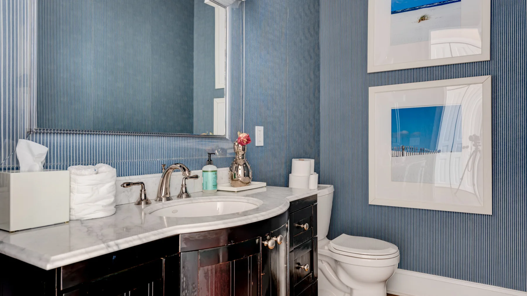 Un baño con lavabo y sanitario junto a paredes azules a rayas.