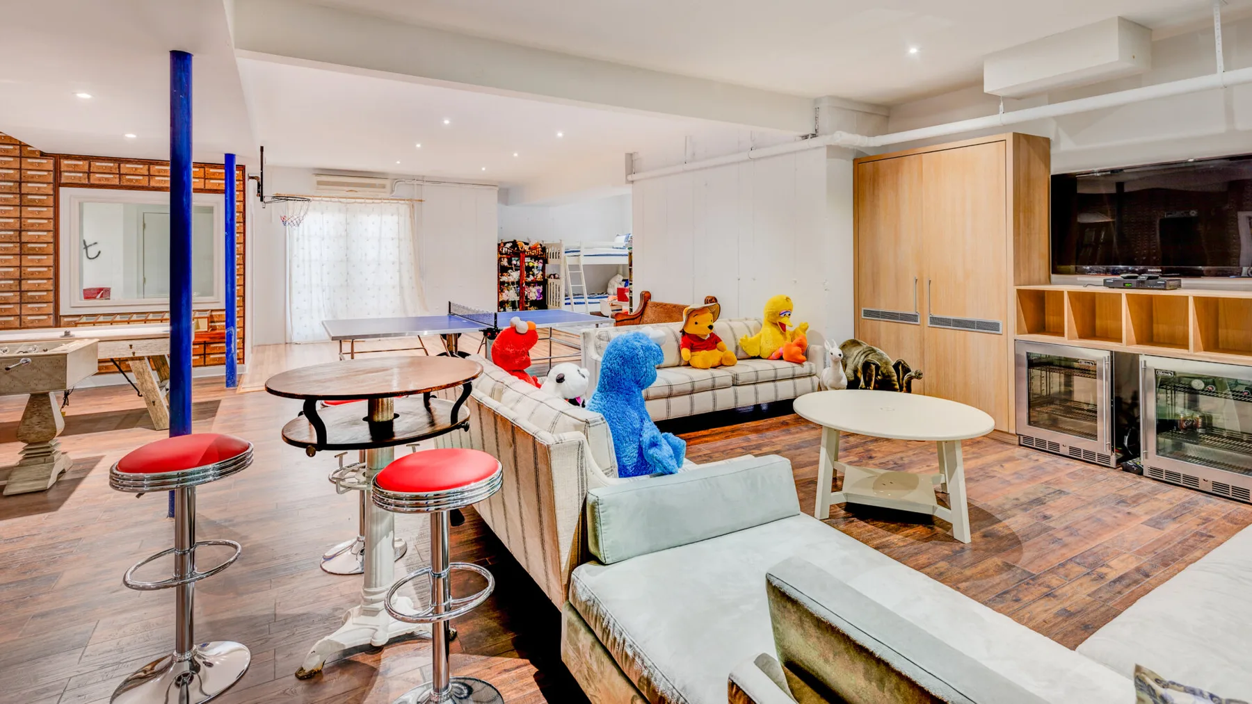 Una luminosa sala de estar de concepto abierto tiene sofás, una mesa de centro y una barra de cocina con taburetes.