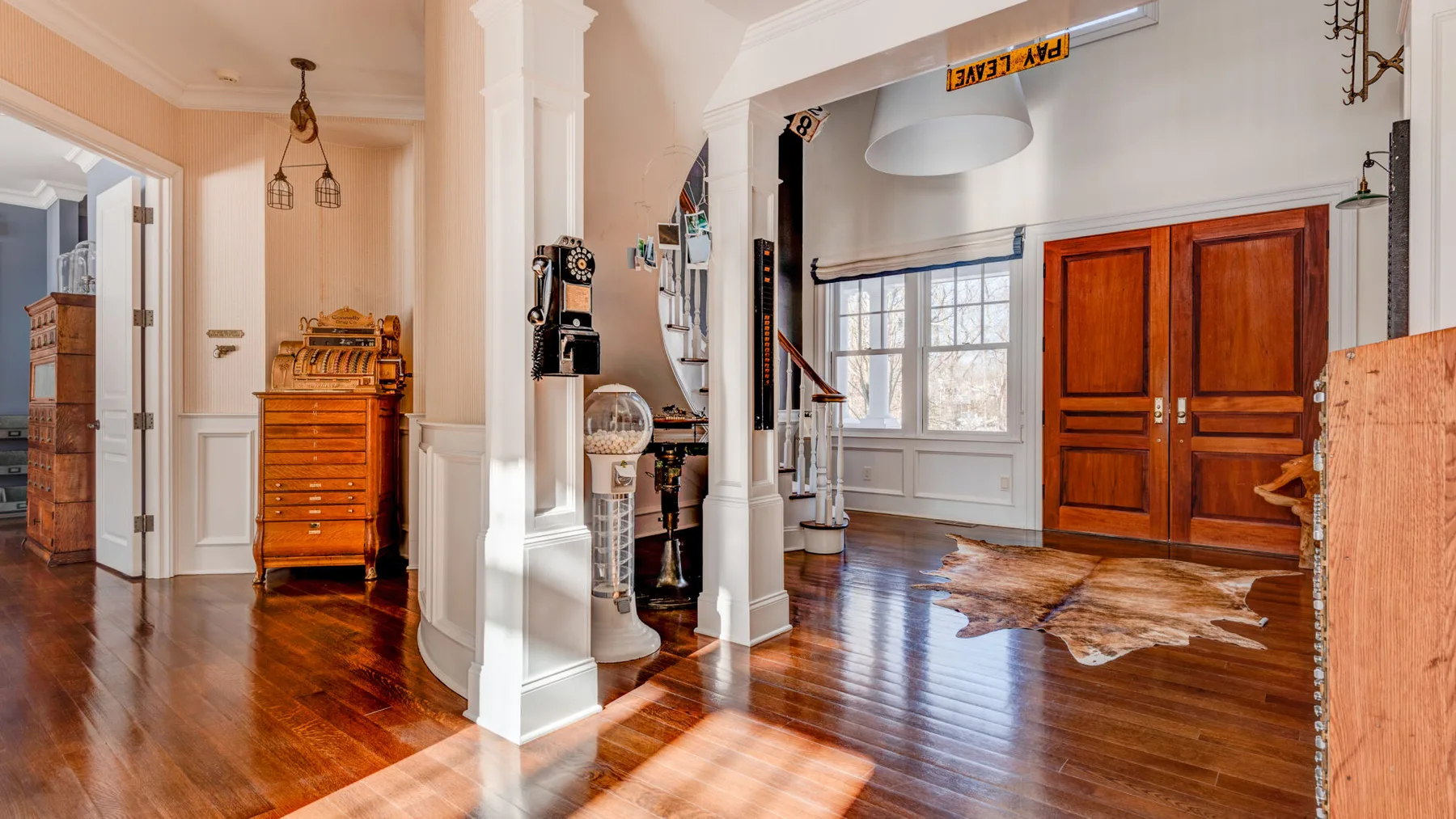 Interior luminoso con suelos de madera pulida, columnas blancas y puertas dobles de madera.