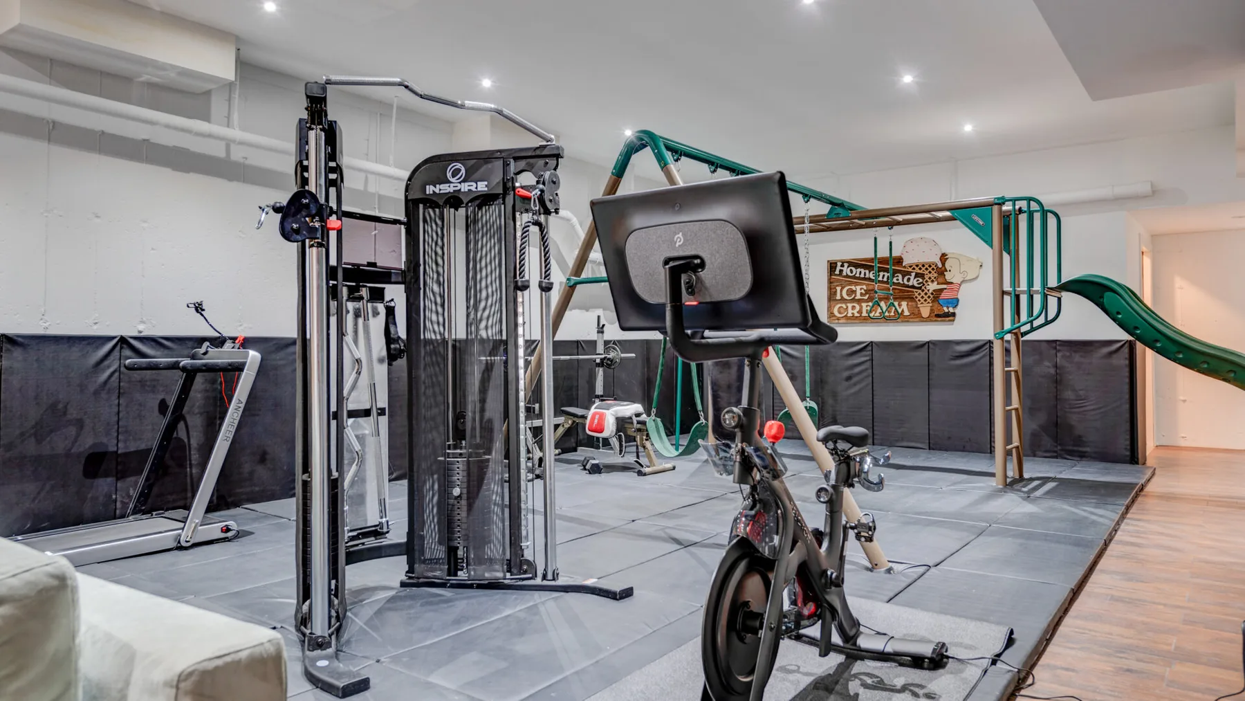 Un gimnasio interior con equipo de ejercicio y una estructura de juegos.