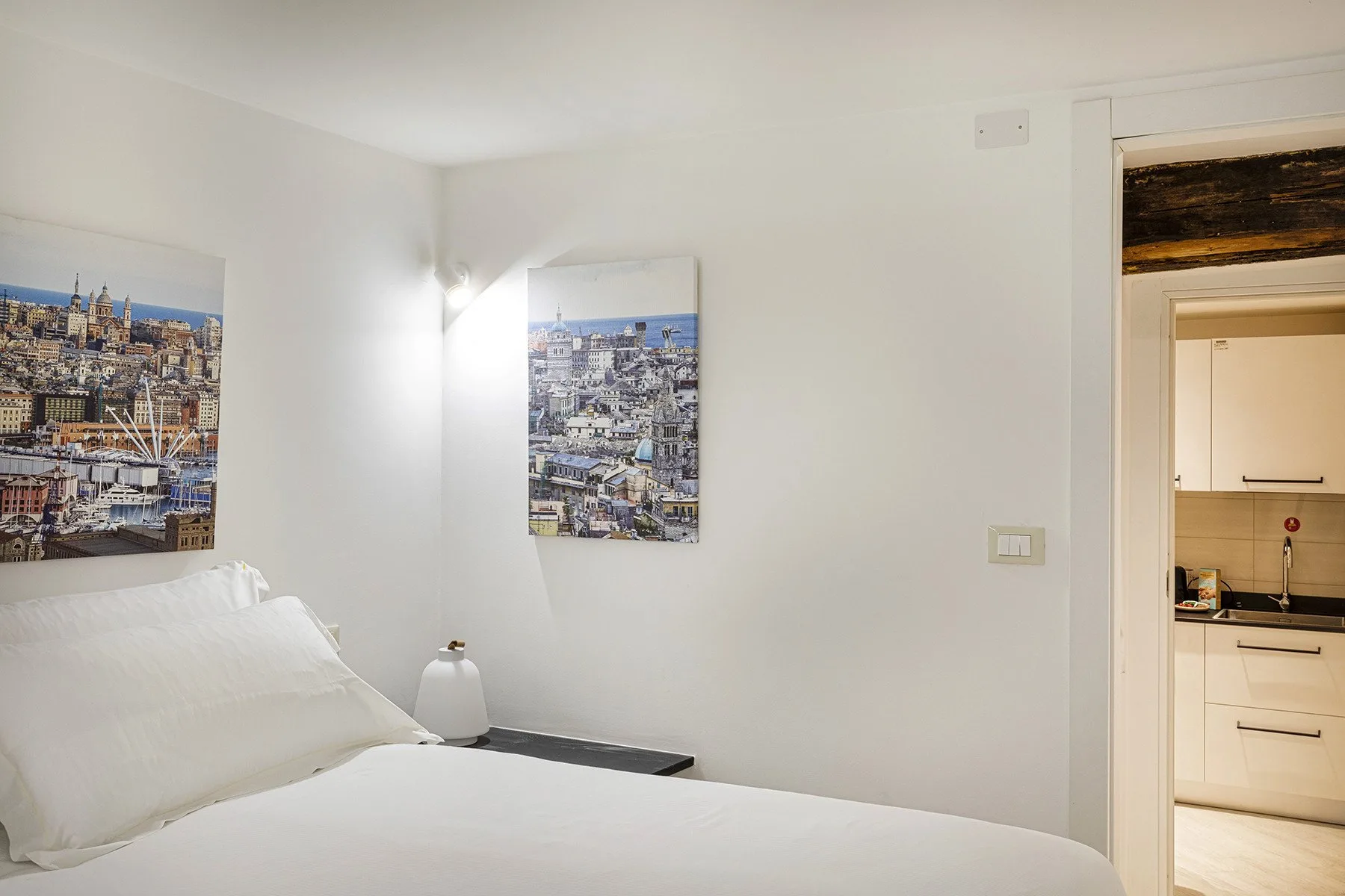 Un dormitorio con una cama blanca y fotografías urbanas enmarcadas en las paredes.
