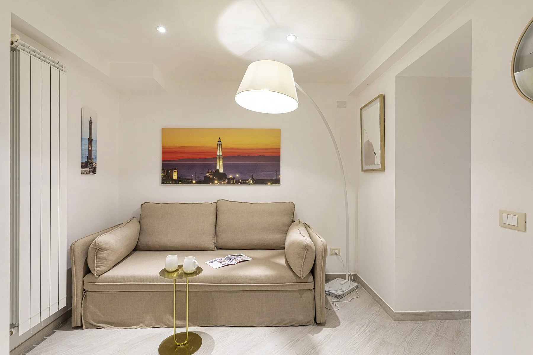 Sala de estar con un sofá beige bajo una colorida pintura urbana.