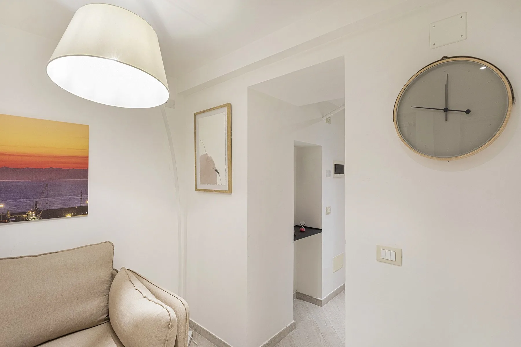 Una sala luminosa con asientos claros, cuadros y un gran reloj redondo.