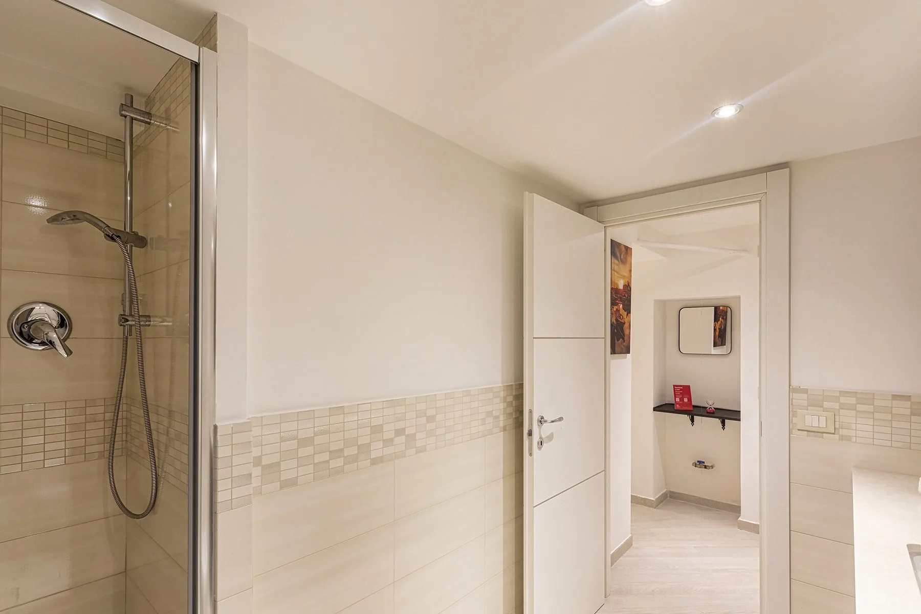 Un baño alicatado con ducha y una puerta abierta.