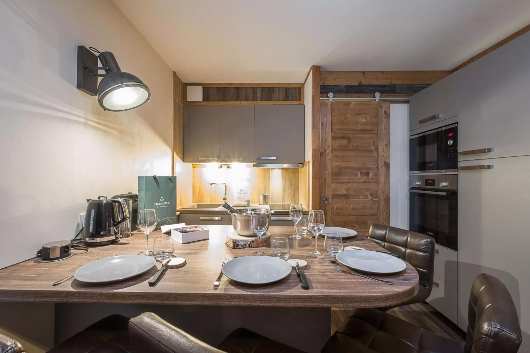 Una mesa de comedor con vajilla está en una cocina compacta.