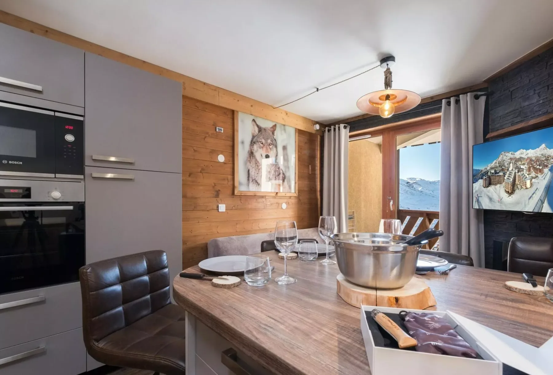 Una cocina abierta con comedor y una mesa puesta junto a una ventana amplia.