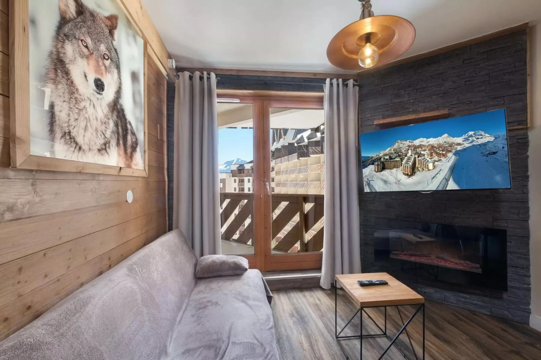 Sala de estar con asientos, una mesa de centro y un televisor sobre una chimenea.