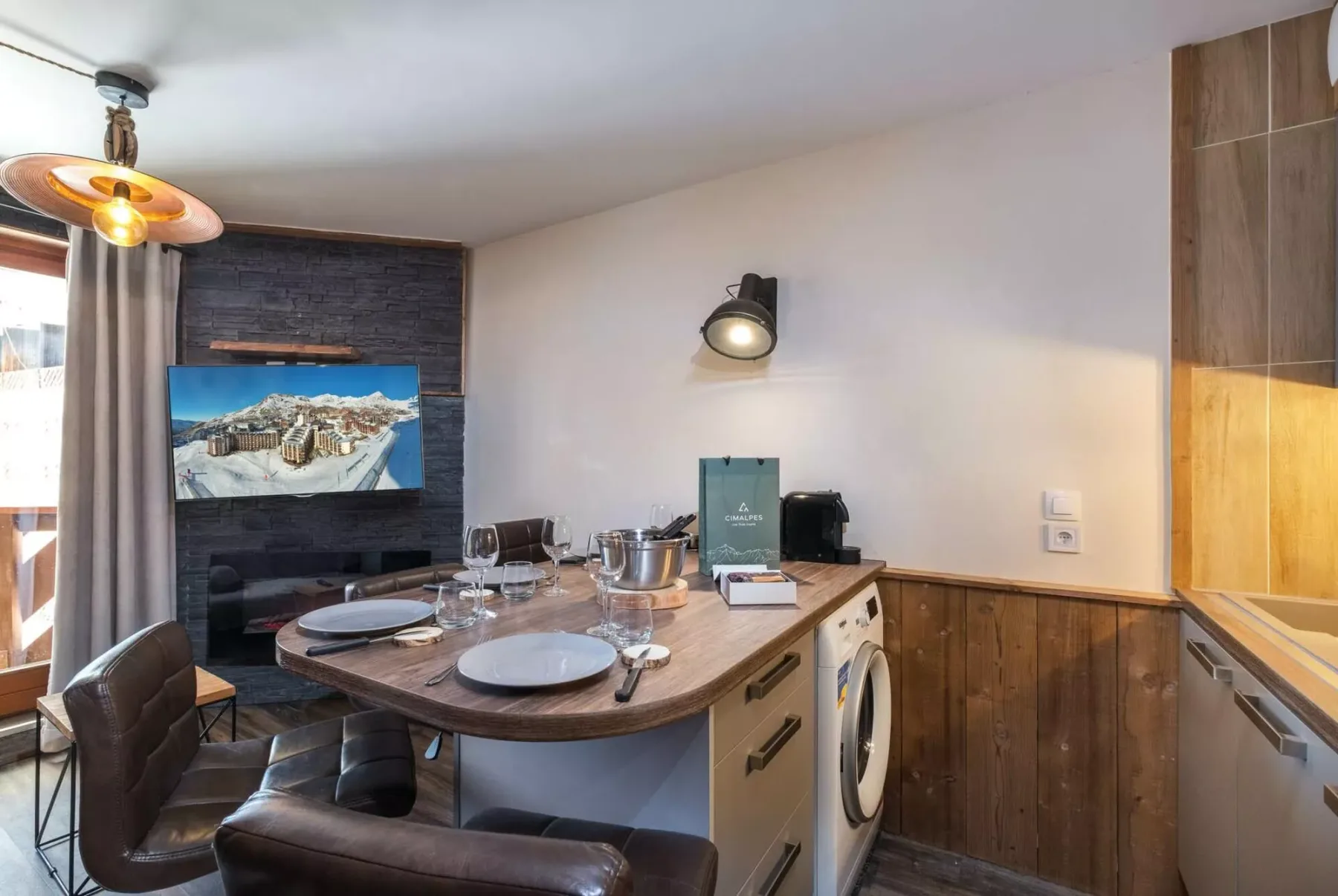 Una cocina compacta con comedor, mesa y televisor montado en la pared.
