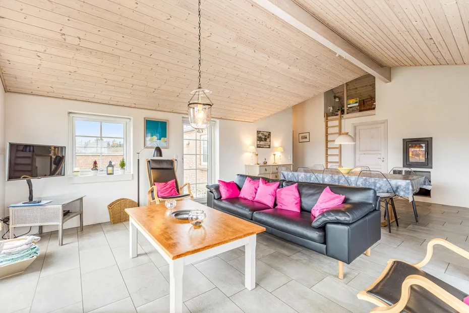 A bright living and dining area with a dark sofa and a wooden coffee table.