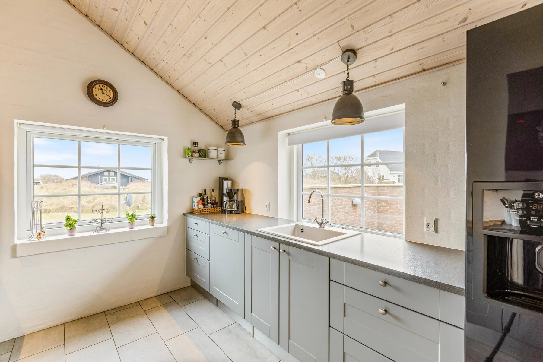 Una cocina luminosa con muebles claros, una encimera y ventanas con vistas al exterior.
