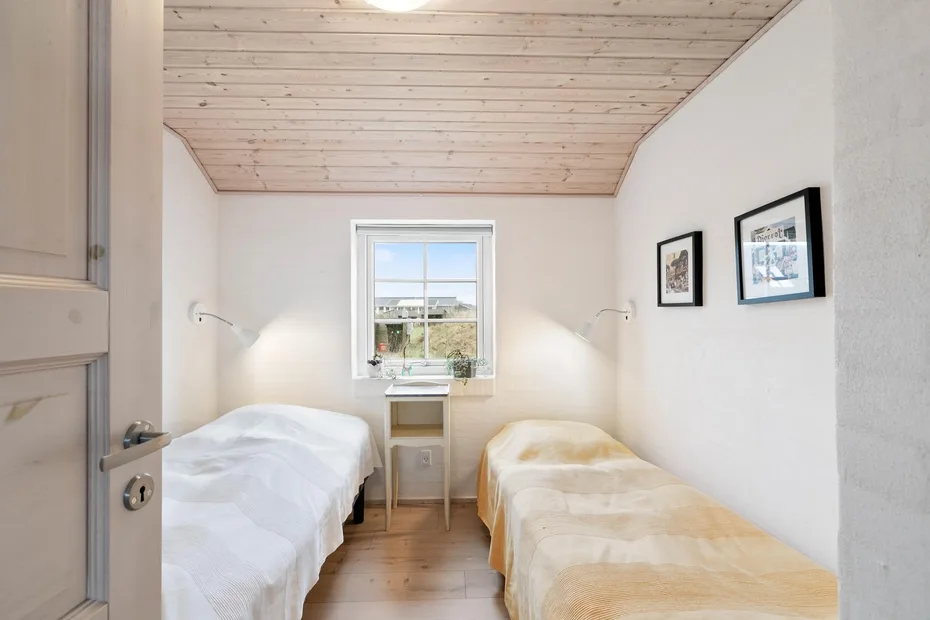 Un dormitorio luminoso con dos camas individuales y una ventana.