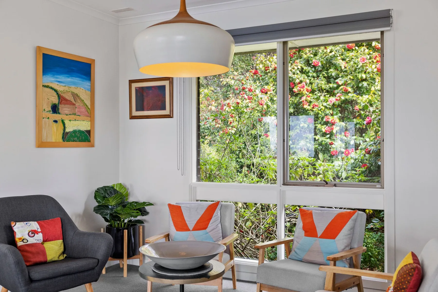 Una sala luminosa con asientos junto a una ventana grande con vistas a la vegetación.