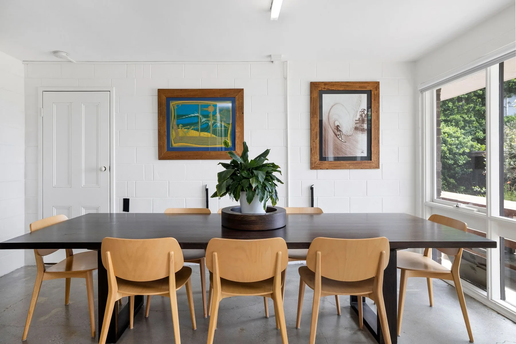 Comedor con una mesa larga y sillas bajo cuadros enmarcados.