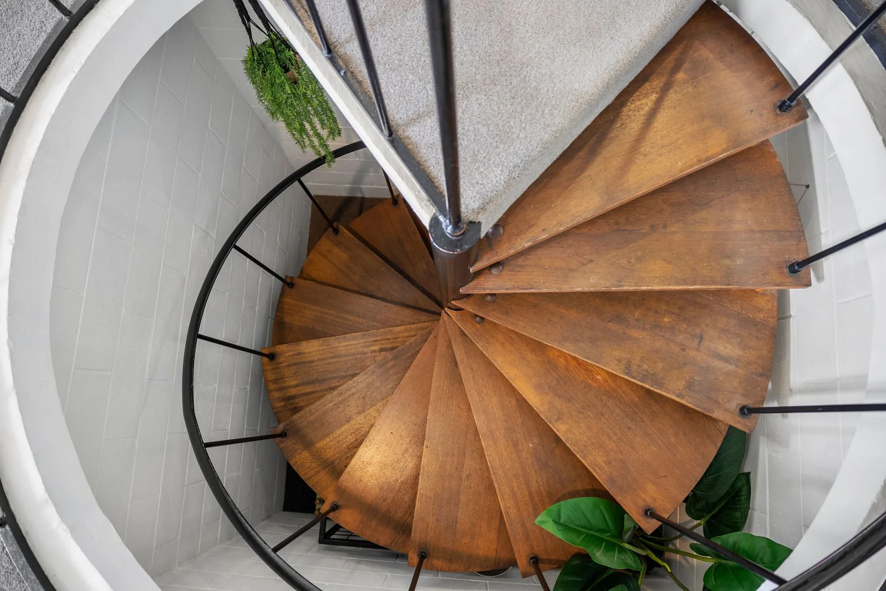 Una escalera curva de madera gira alrededor de un soporte central.