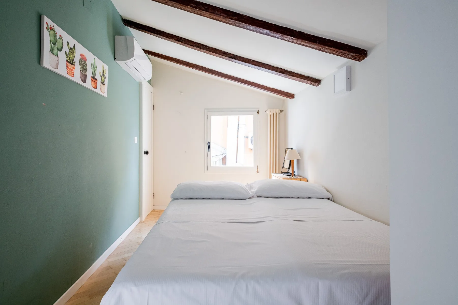 Un dormitorio con una cama bajo vigas de madera vistas en el techo.