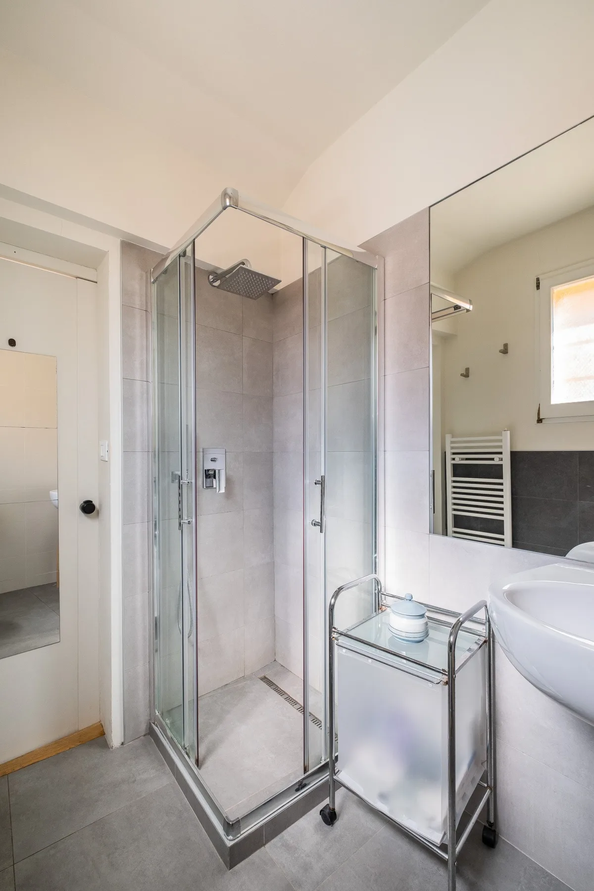 Un baño con ducha de vidrio, lavabo y espejo de pared.