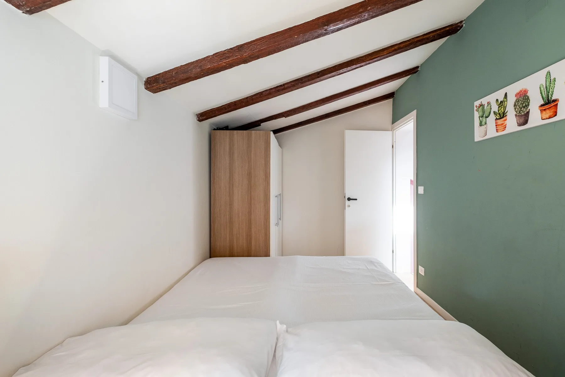 Un dormitorio con una cama, un armario de madera y una puerta abierta.