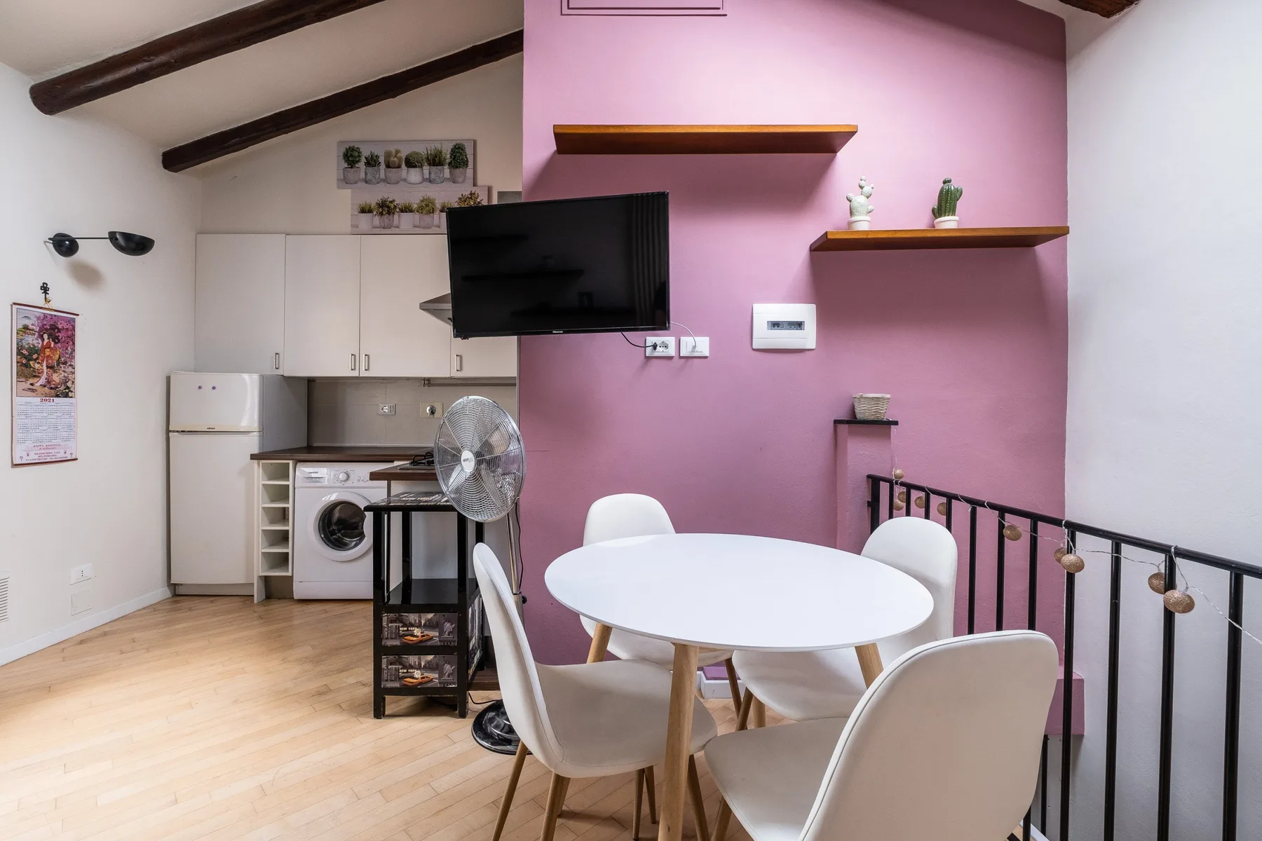 Un comedor con una mesa blanca y sillas junto a una cocina compacta.