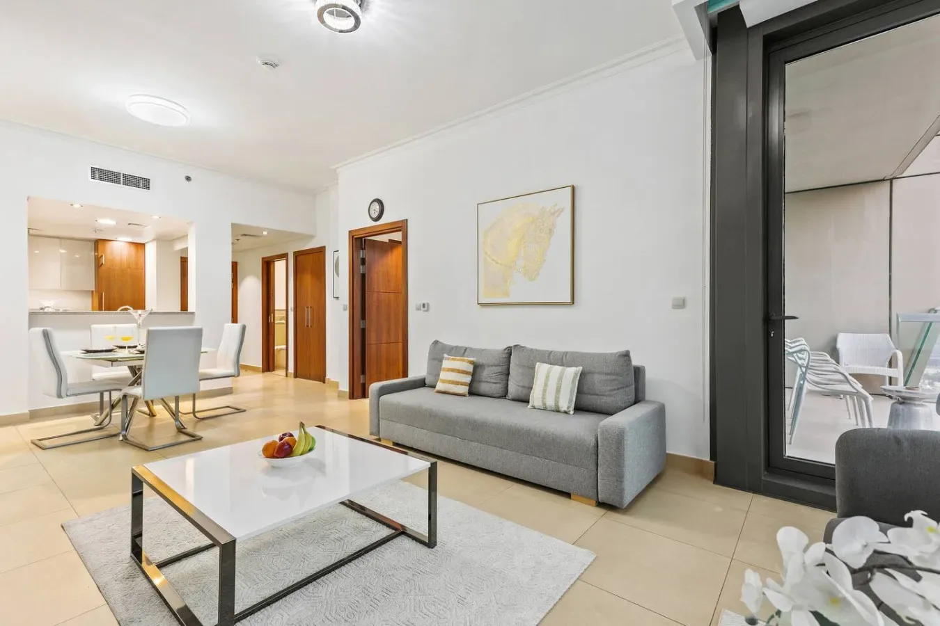 A bright living room with gray seating and a coffee table beside the dining area.