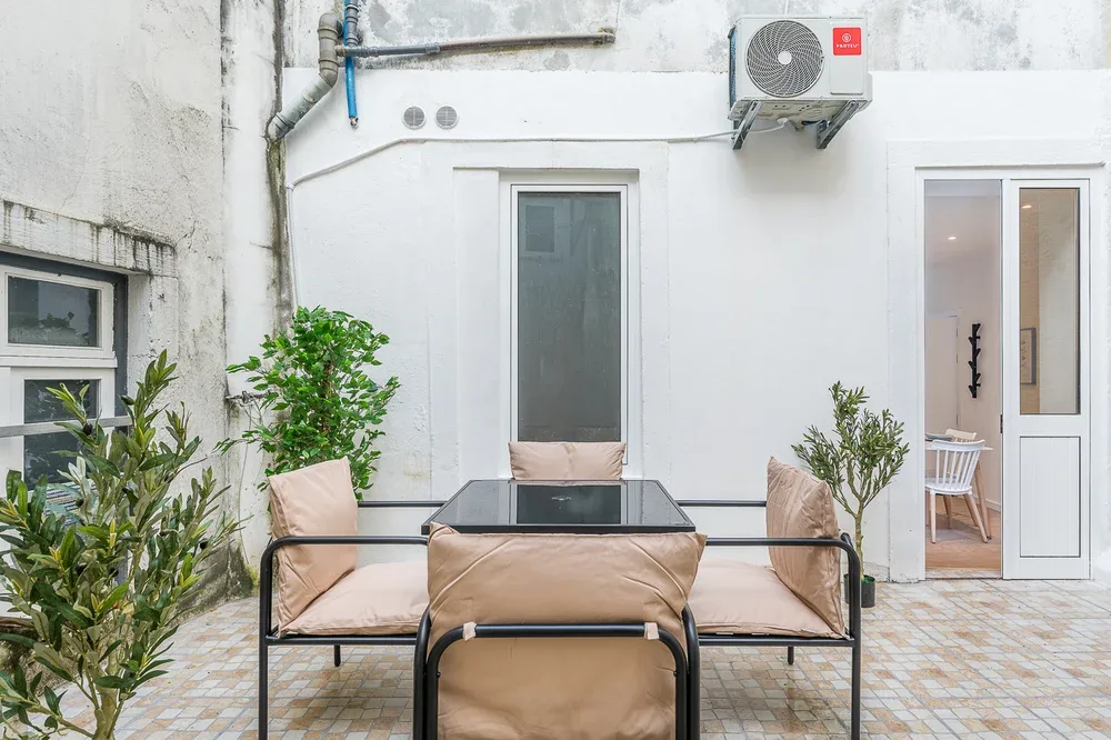 An outdoor patio has cushioned seating, a table, and potted plants.