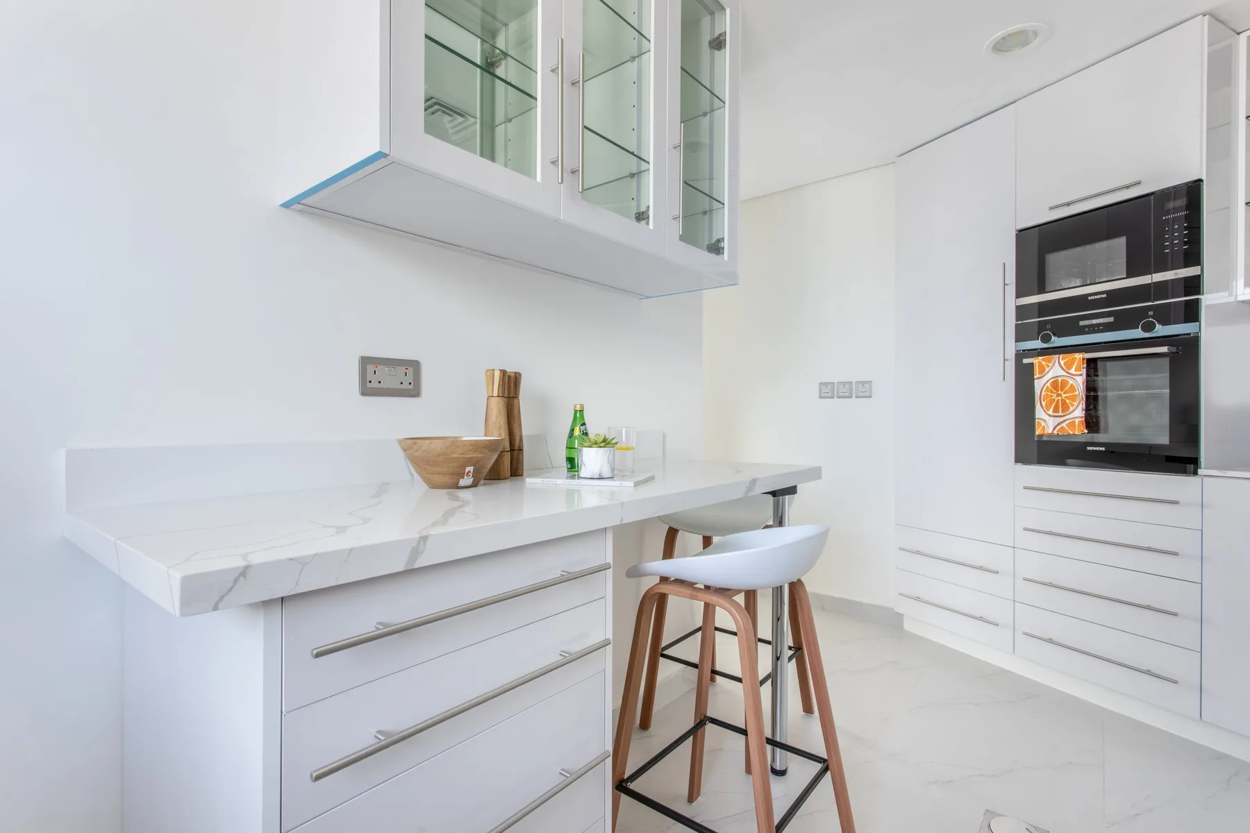 A bright modern kitchen with white cabinetry and a breakfast counter.