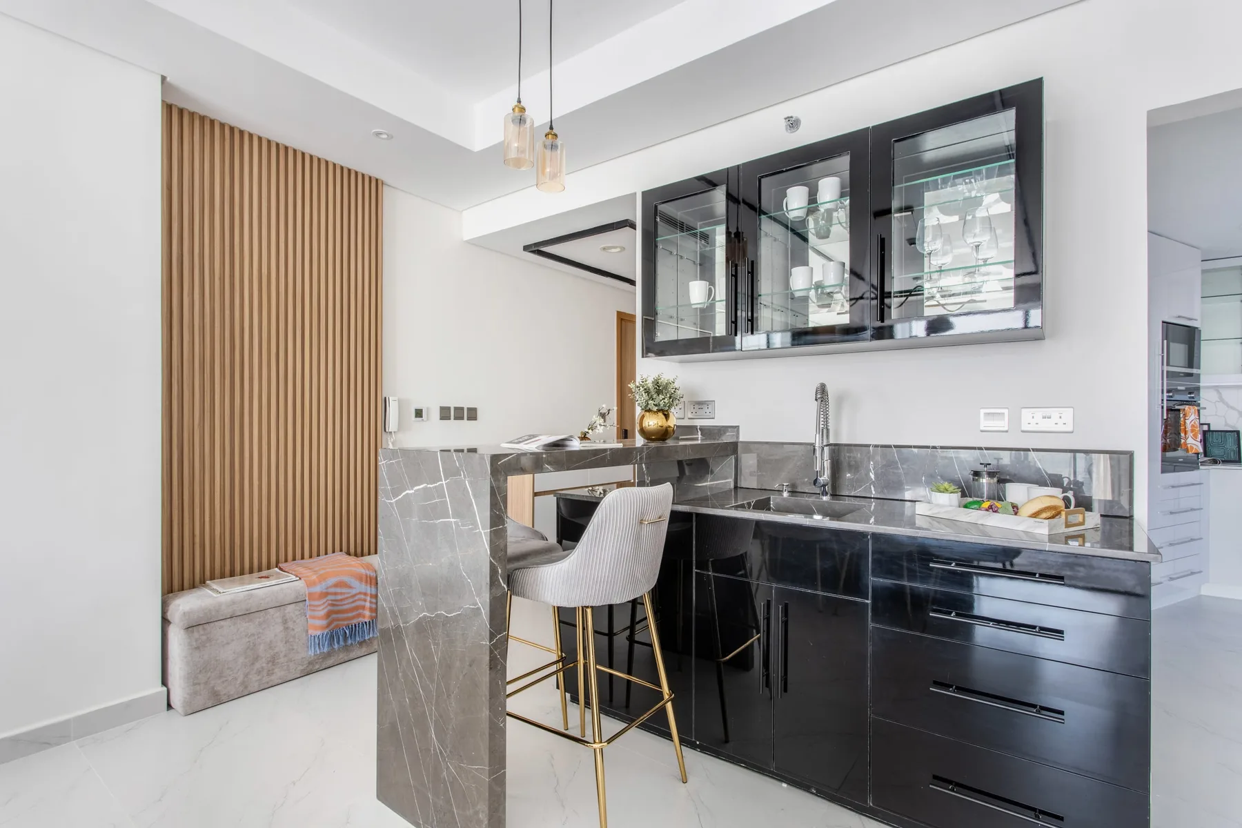 A modern kitchen with dark cabinetry, a marble island, and bar seating.