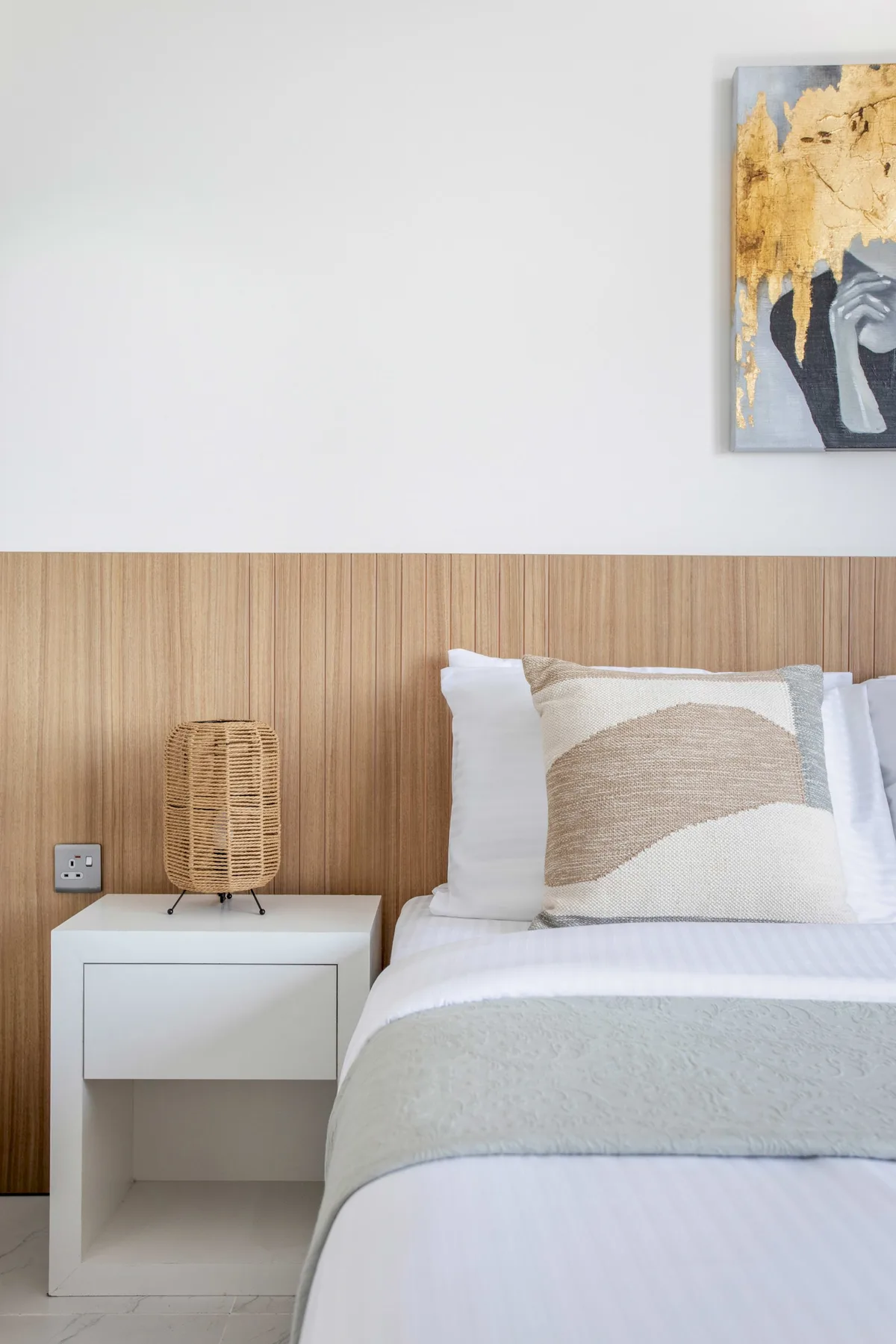 A bedroom with a neatly made bed and a bedside table.