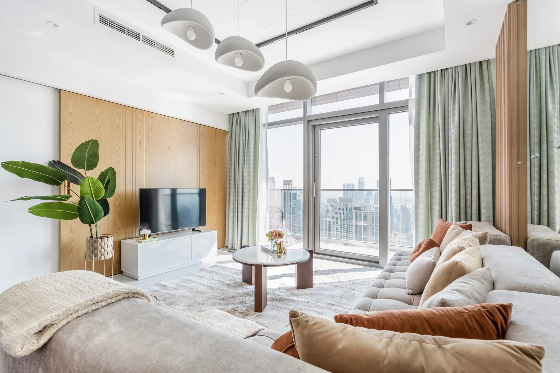 A bright living room with a sofa, television, and large windows.