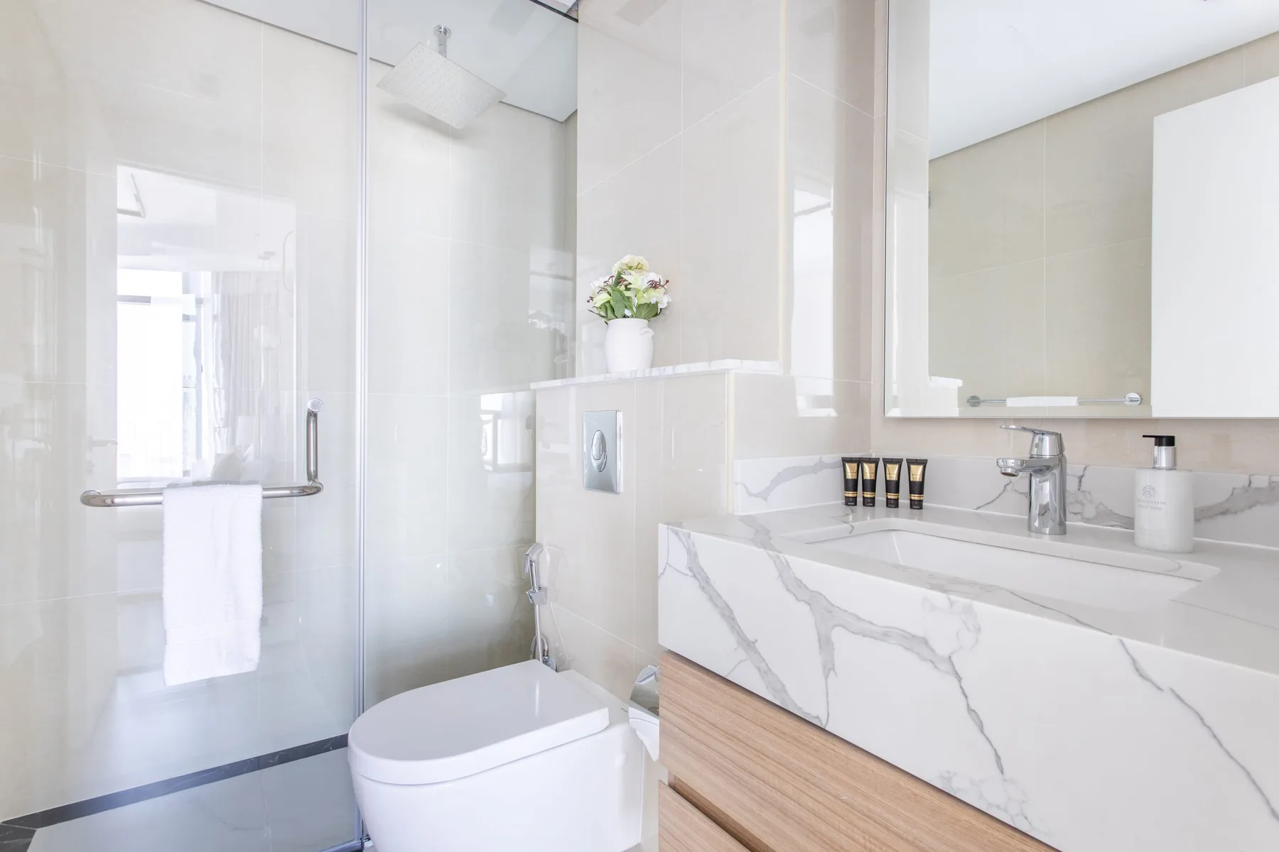 A bright bathroom with a glass shower and a wide vanity.