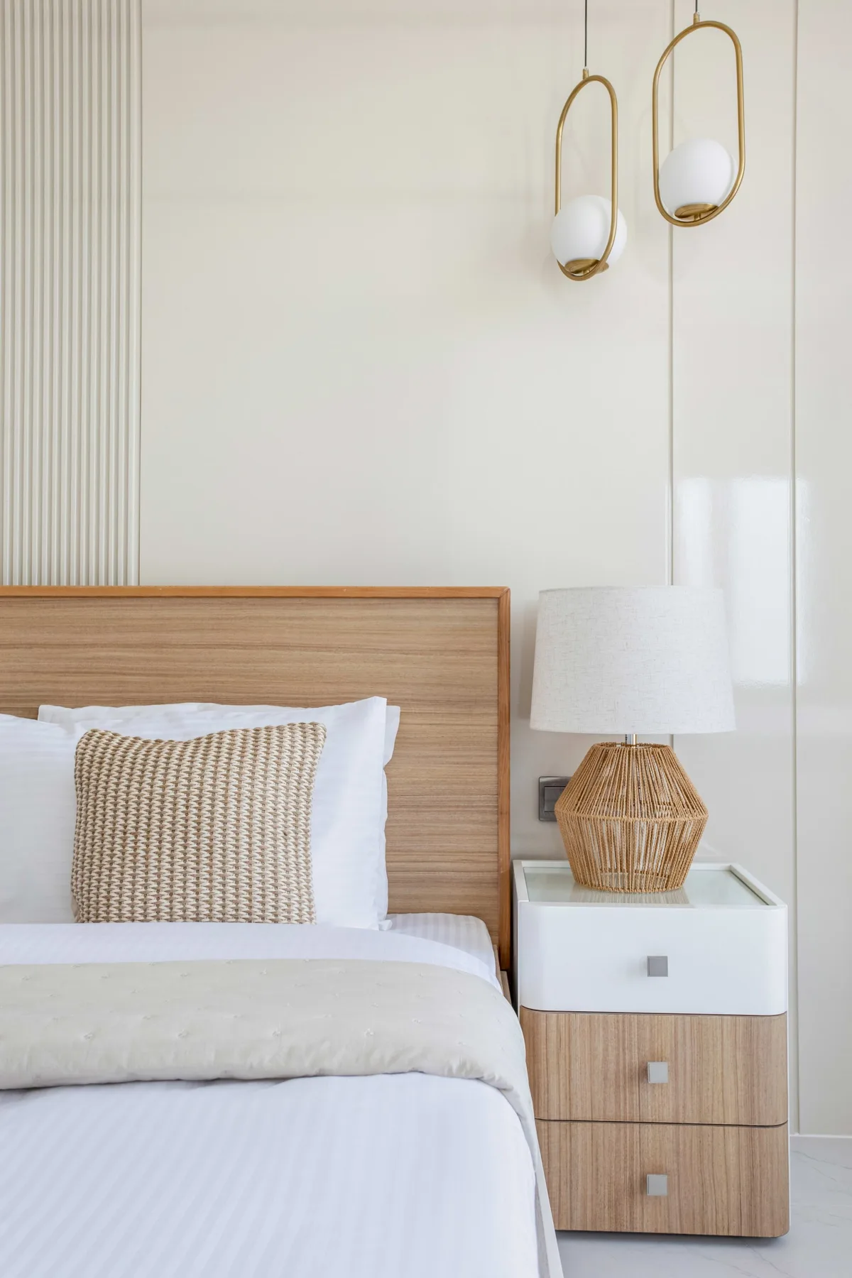 A bright bedroom with a neatly made bed and a bedside table.