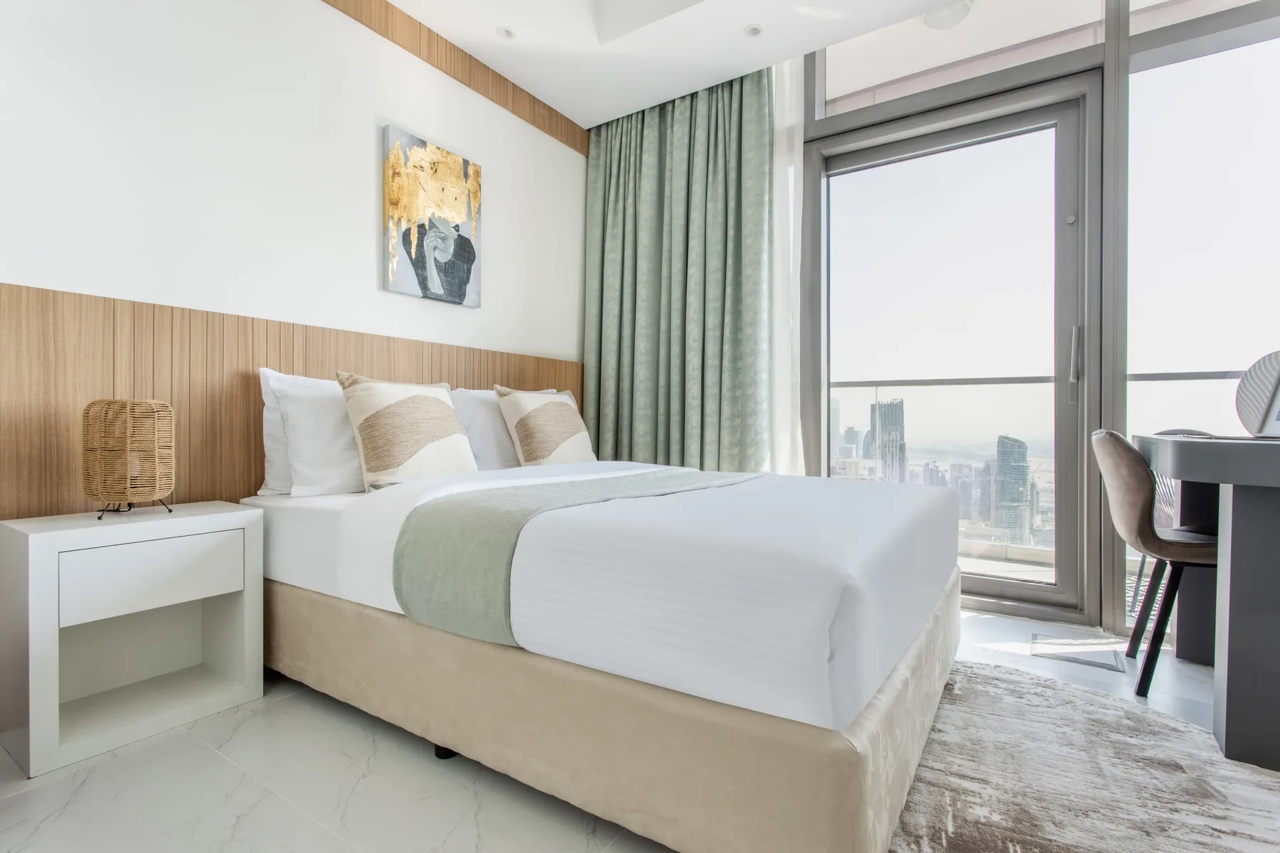 A bright bedroom with a neatly made bed beside a large window.