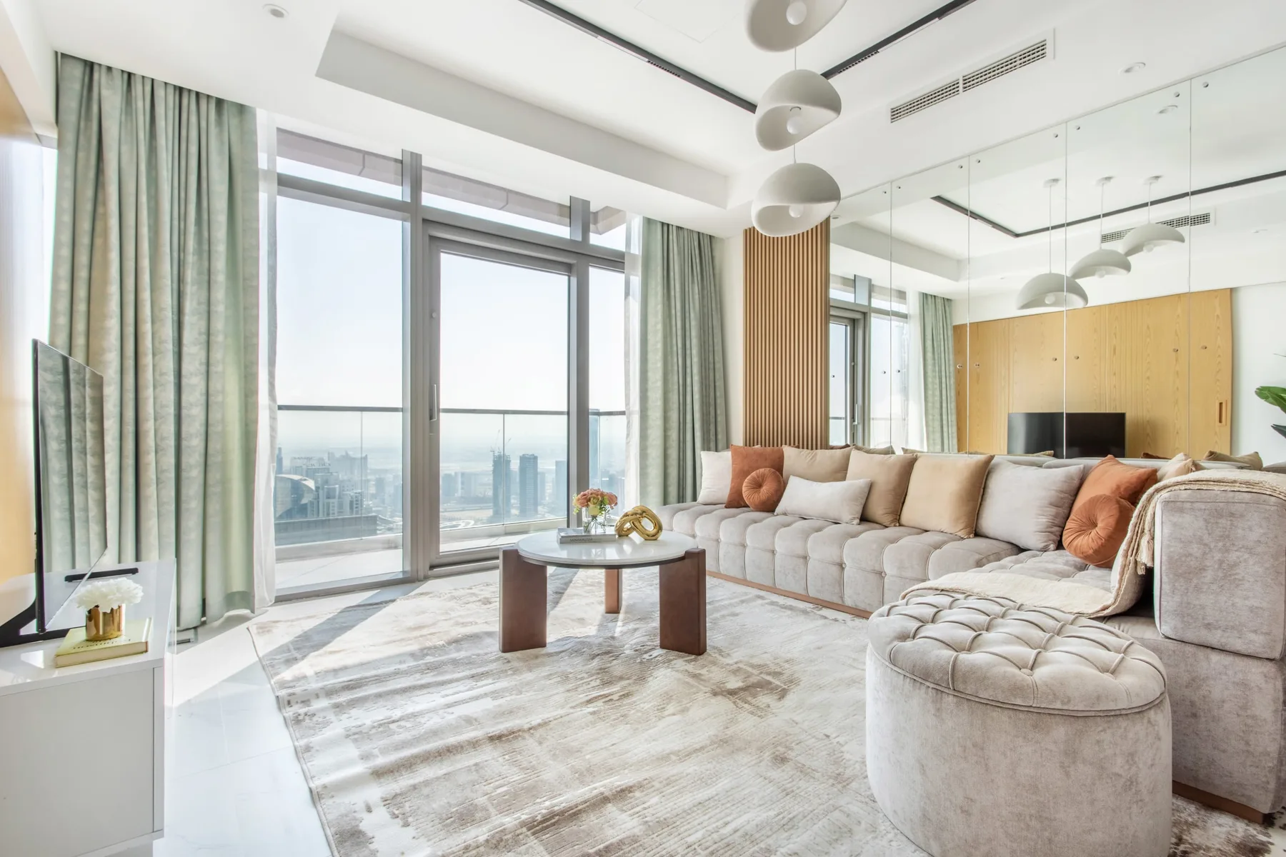 A bright living room with floor-to-ceiling windows and a large sectional seating area.