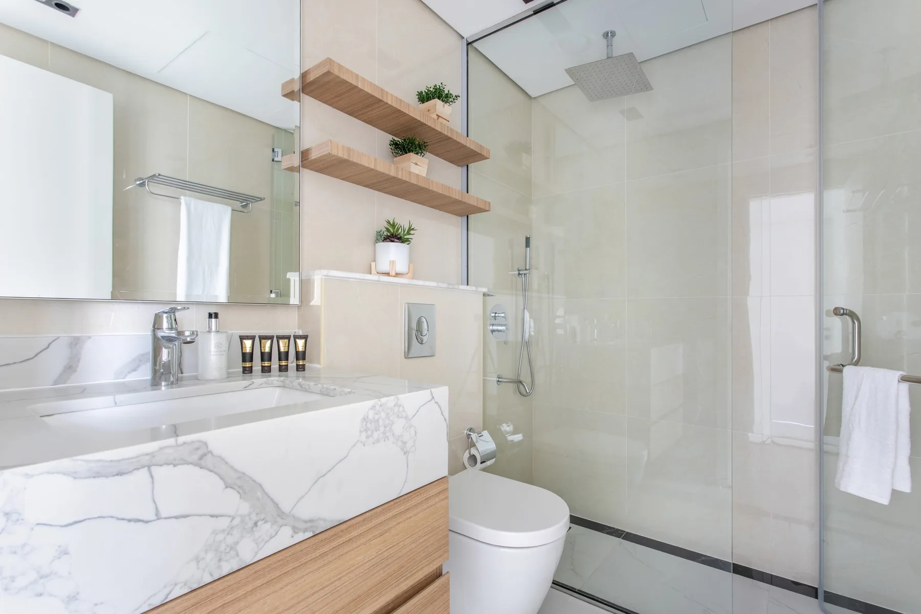A bright bathroom with a marble-patterned vanity and glass shower.