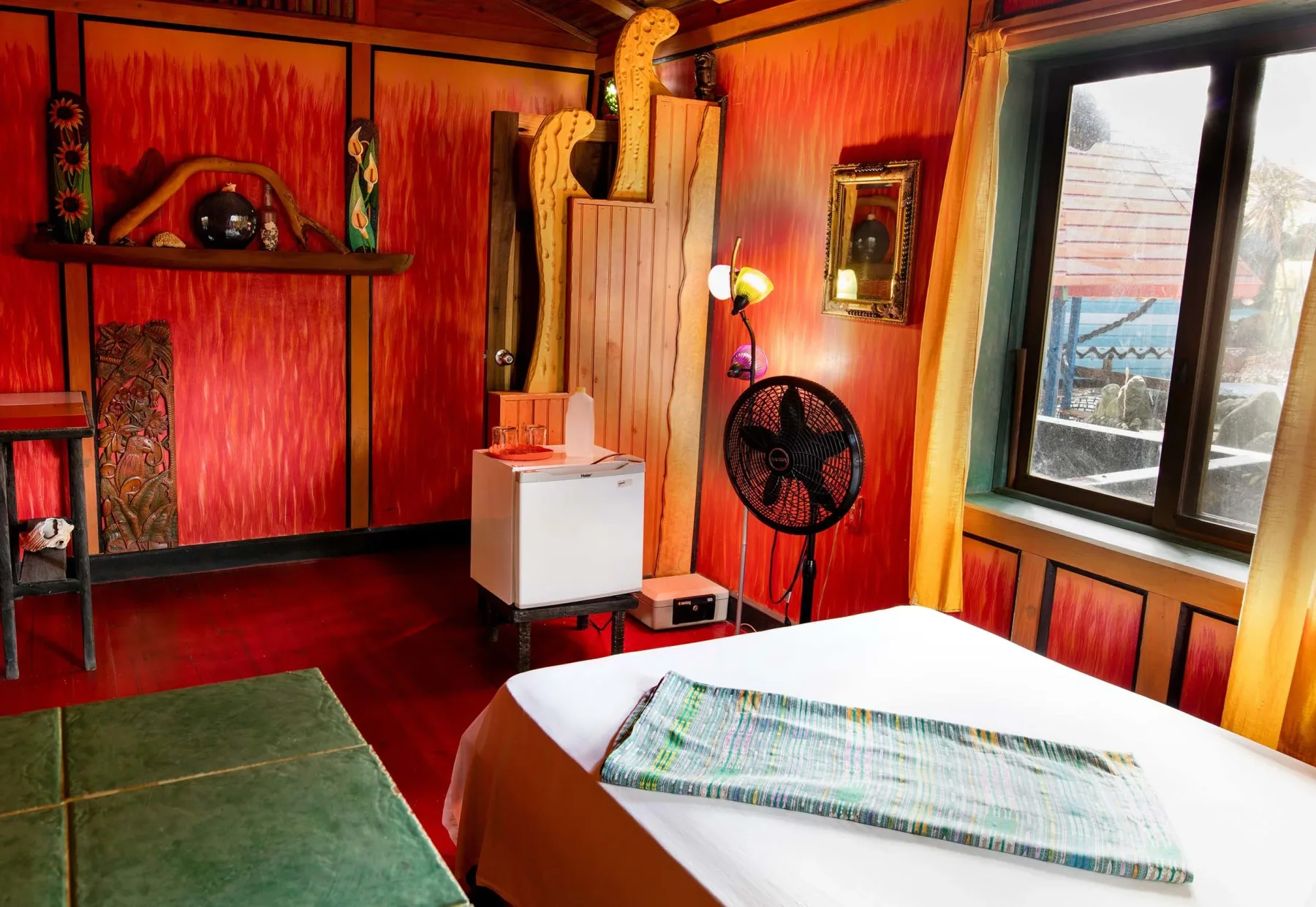 Interior de la cabaña Dalillama con paredes rojas y una cama.