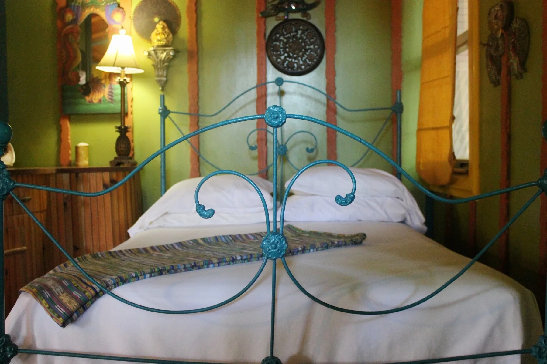Interior de la cabaña Camasutra con una cama queen y un cabecero de hierro azul.