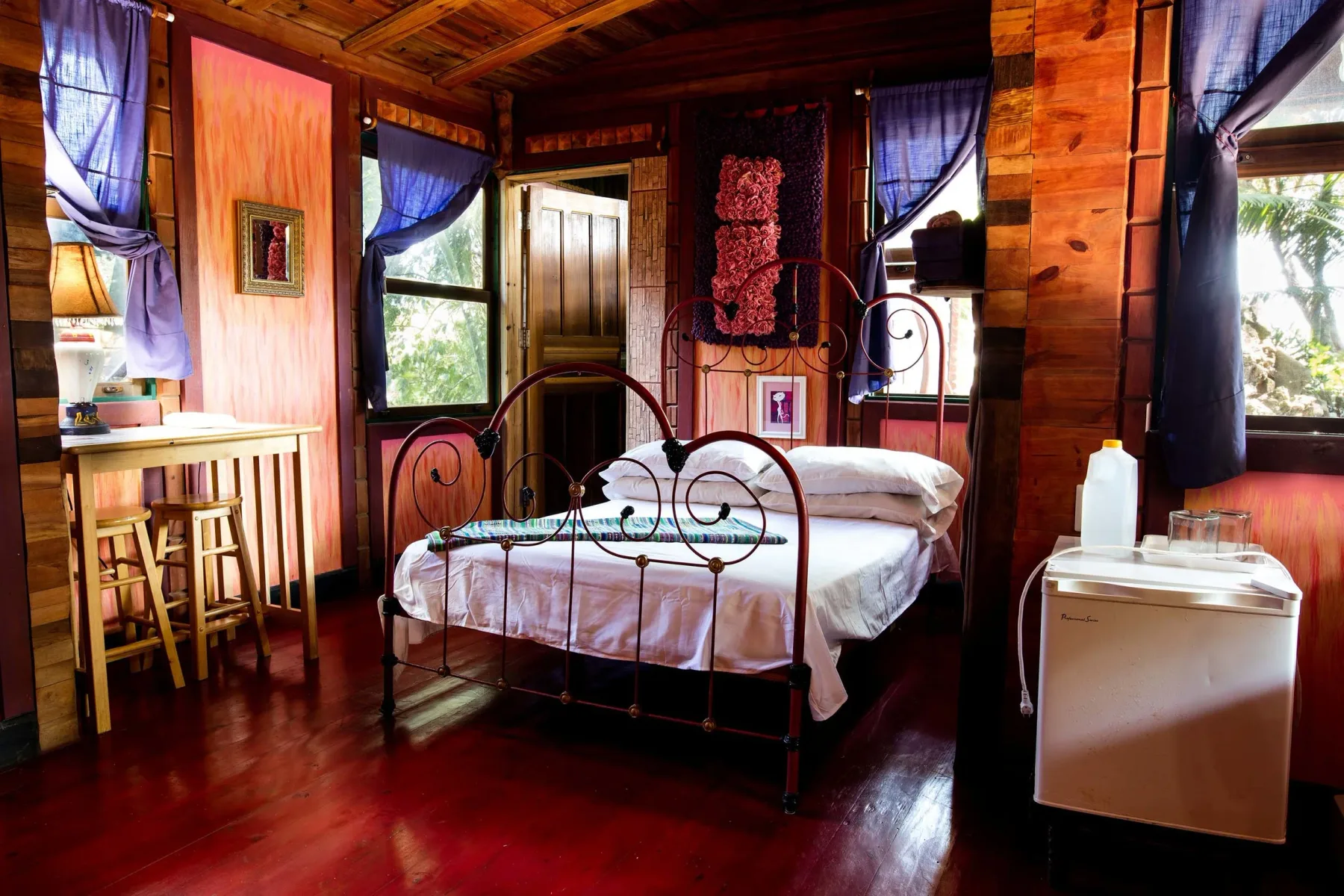 Interior de la cabaña Shagrilla con un escritorio, sillas, una cama queen y un minirrefrigerador.