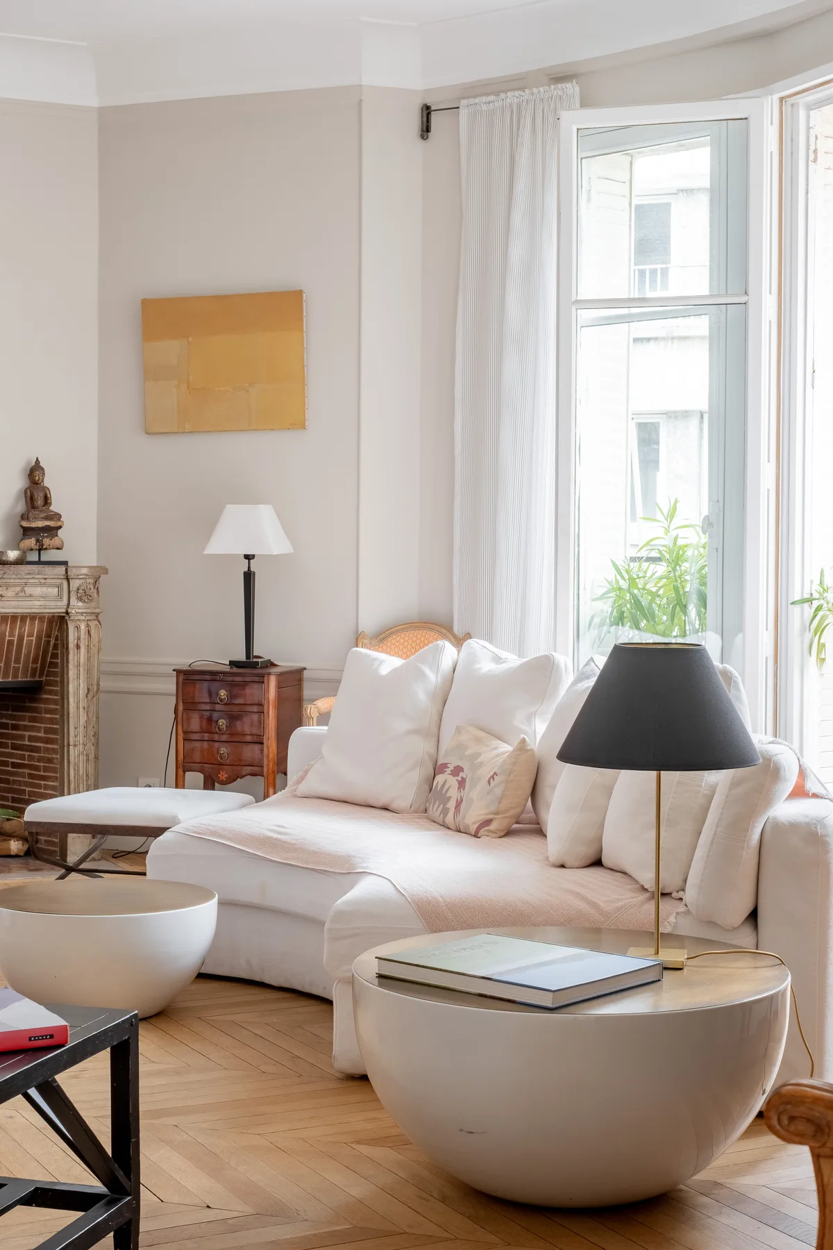 A bright living room with white seating beside tall windows.