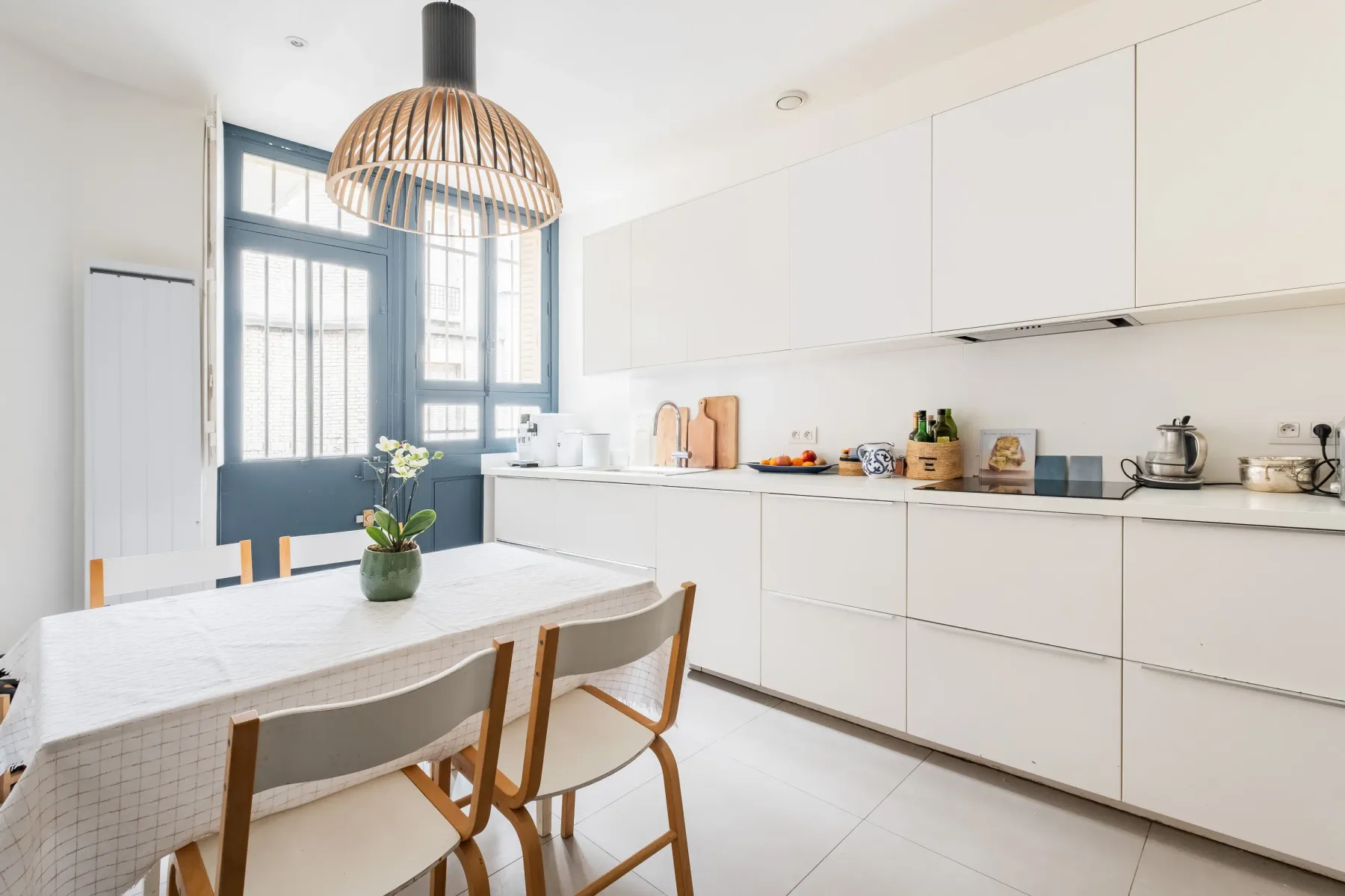 A bright kitchen with white cabinetry and a dining table beside the windows.