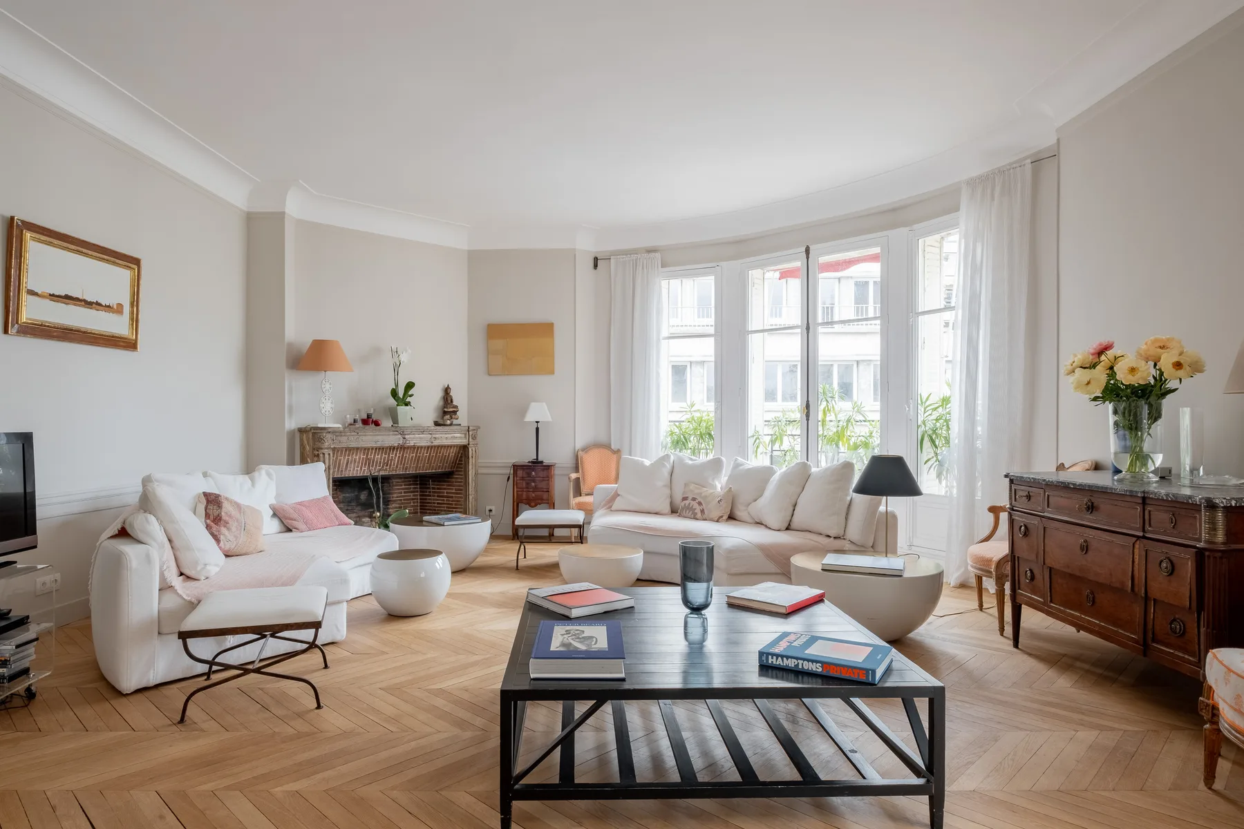 A bright living room with seating arranged around a coffee table beside large windows.