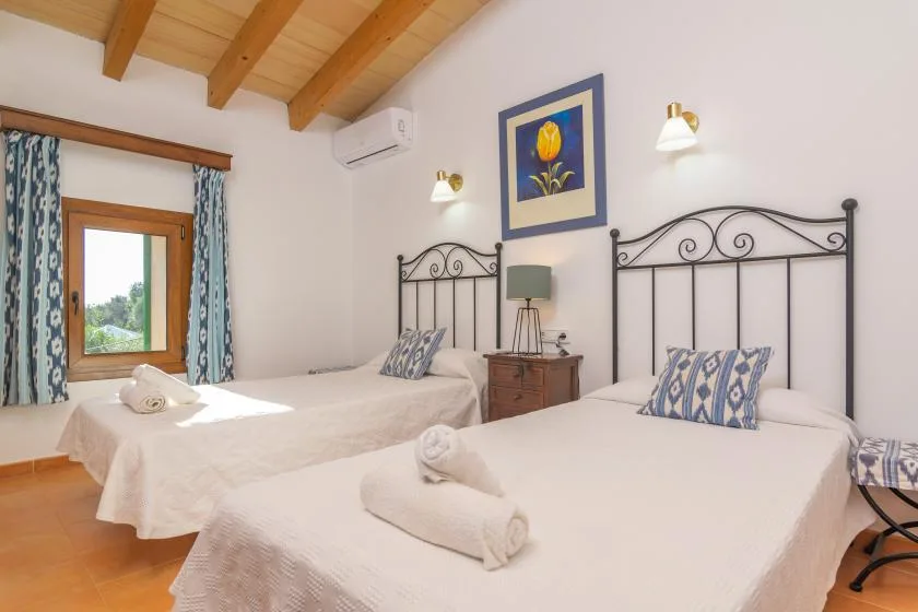 A bedroom with two beds, patterned curtains, and a framed floral picture.