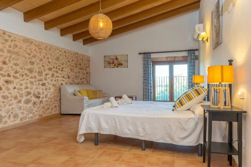 A bedroom with a bed, seating, and glass doors opening onto a balcony.