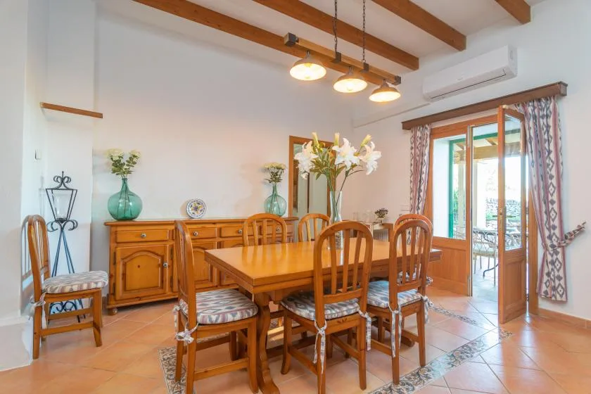 A wooden dining table and chairs sit beside glass doors opening onto a patio.