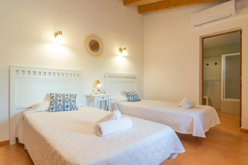 A bright bedroom with two beds and a small bedside table.
