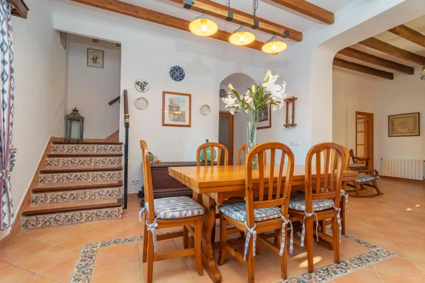 A dining room with a wooden table and chairs beneath exposed ceiling beams.