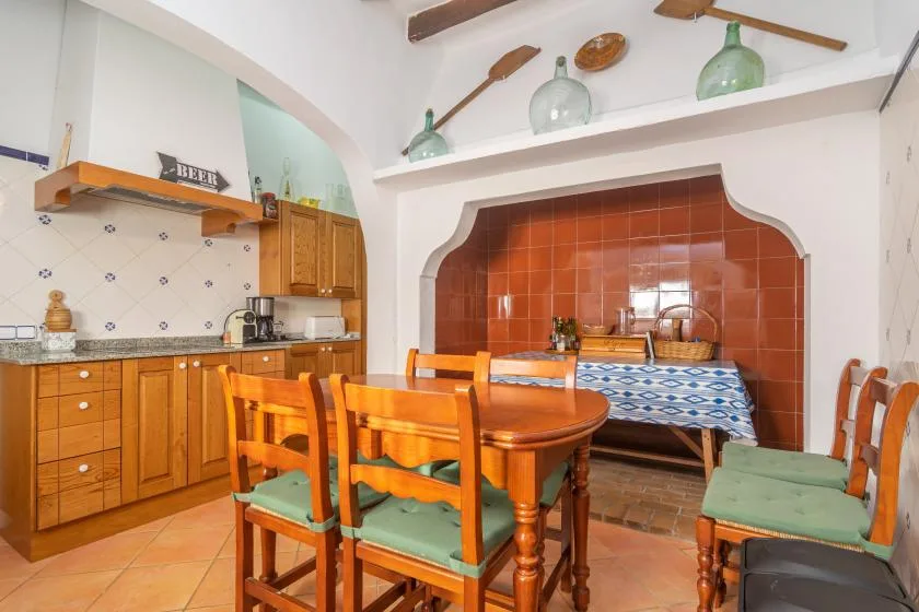 A dining area with a wooden table and chairs beside a kitchen counter.