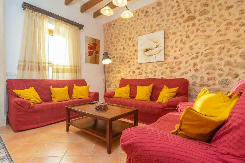 A living room with red seating, yellow cushions, and a wooden coffee table.